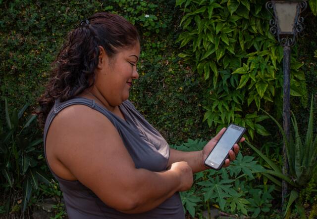 A woman in El Salvador looks at her cellphone